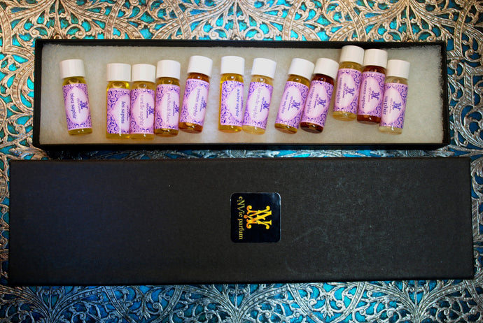 group photo of discovery set of 12 original silver eNVie collection perfume oils in 2ml in a long black box.  No inserts.